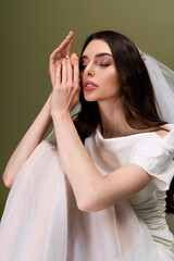 Naklejka premium Captivating beauty of a young bride in blissful reflection against a soft green backdrop