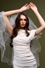 Naklejka premium Beautiful young bride elegantly posing with flowing veil in serene setting