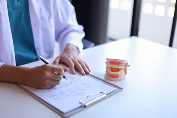 Dentist working in office writing diagnose oral health issues.