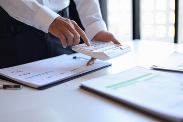 Businessman working in office using calculator.