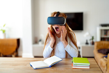 Young woman reacting to virtual reality experience while sitting at a table in her home