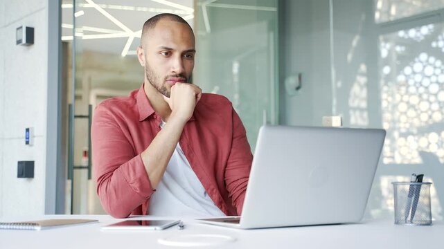 Thoughtful businessman working on laptop in business office. Manager thinking about problem solving sitting at workplace. An entrepreneur is engaged in a task or is busy with a project on computer