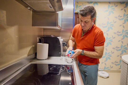 A middle-aged man at home in the morning makes coffee and serves it. - Powered by Adobe