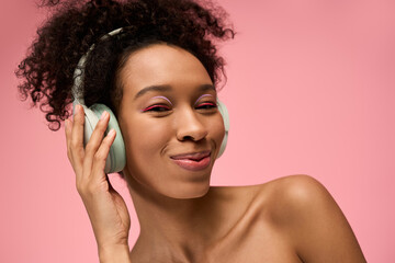 Joyful young woman enjoying music with headphones against a vibrant pink background