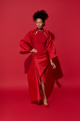 Young woman in radiant red attire exuding confidence against a bold crimson backdrop