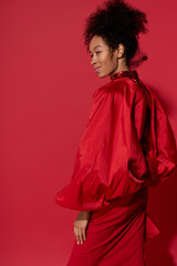 Young beautiful woman in bold red attire poses gracefully against a vibrant red backdrop