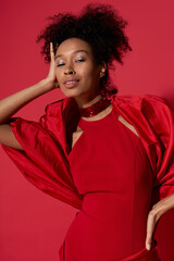 Radiant young woman in striking red outfit exuding confidence and charm against vibrant background