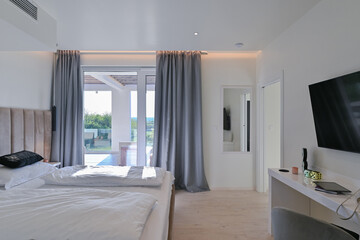 Bright, modern bedroom featuring a comfortable bed, sleek desk, and a large sliding glass door opening to a private balcony with stunning green landscape views, perfect for relaxation and serene