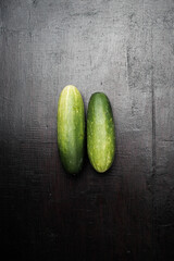 Two cucumbers on a black wooden background