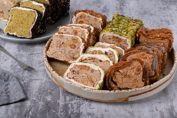 Assortment of sliced ​​Turkish delight with cream filling, pistachio, almond, hazelnut on a gray table. Local name: fistikli fitil lokum