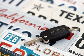 Remote control car keys on US license plates with state names close up. Concept of driving in United States. Reaching a car registration