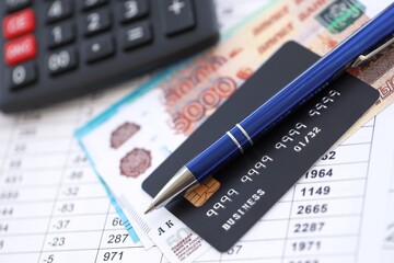 Credit card and pen with russian ruble currency money bills banknotes on calculations document background. Business, financial operations and accounting in Russian Federation