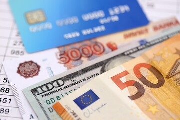 Credit card and russian rubles, euro and US dollar bills banknotes on calculations document background. Currency exchange online and convertations concept