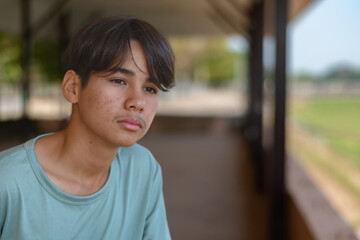 A quiet moment of melancholy. This middle schooler, dressed in a blue t-shirt, sits alone with a sad, introverted expression. Capturing the complexity of youthful solitude.