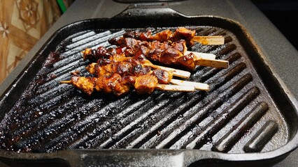Smoky grilled skewers on hot cast iron pan. street food.
