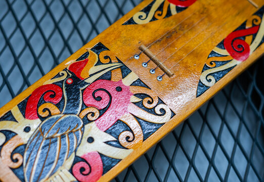 Macro shot of a traditional Sape' musical instrument from Kalimantan, Borneo, Indonesia. Featuring colorful hand-painted Dayak tribal patterns and strings on the wooden body.