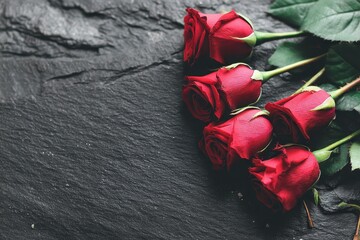  Red roses laid on a dark slate or stone surface.