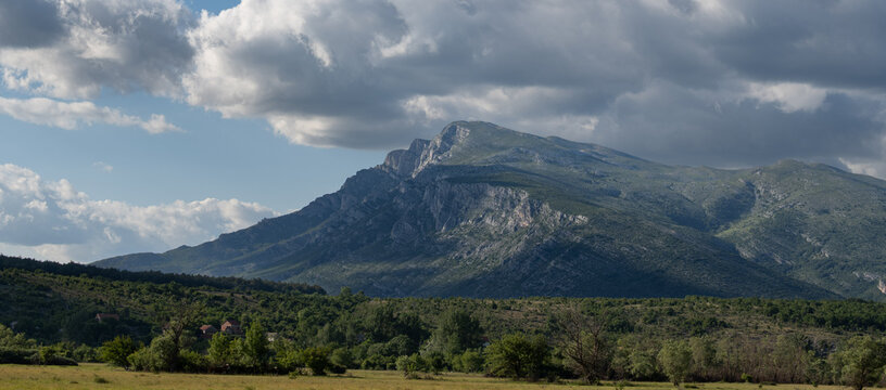 Dramatic mountain landscape with rural valley under cloudy sky, Dinara, Croatia