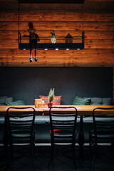 A cozy wooden dining space with plaid pillows, holiday table decor, and a lit overhead display featuring a Christmas bear, glass tree, and miniature house