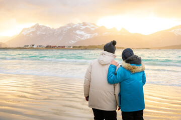 Couple traveller looking at sunset in Reine village, Lofoten, Norway