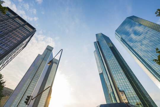 View of towering skyscrapers at financial district piercing the bright blue sky, their glass facades reflecting the sunlight in Frankfurt am Main, Hessen, Germany.