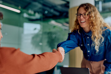 Two businesswomen are shaking hands, celebrating a successful deal and new partnership in a modern office environment © we.bond.creations