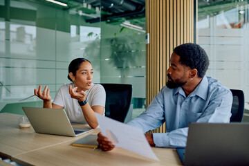 Diverse business colleagues collaborating and discussing marketing data at a modern office boardroom table