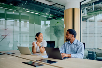 Two diverse business colleagues discussing ideas at an office table. They are collaborating and working together on a project