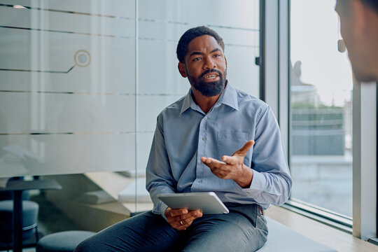 African American man discussing ideas and planning strategy with a colleague in a modern business office setting - Powered by Adobe