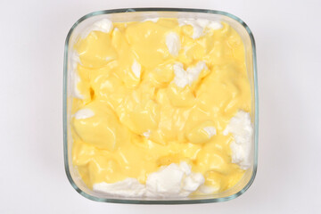 An overhead view shows a glass dish filled with snenokle dessert - floating egg white meringues in vanilla custard