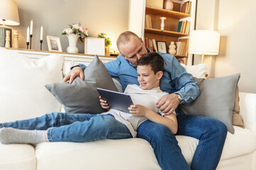 Father and son bonding and using digital tablet at home. Single dad and his son using digital tablet at home.