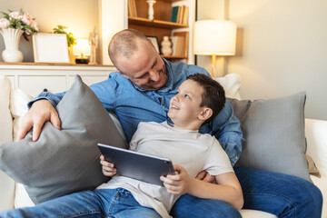 Shot of a father and son sitting on the sofa and using a digital tablet together. Learning about technology is a bonding experience.