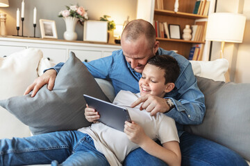 Father and son bonding and using digital tablet at home. Single dad and his son using digital tablet at home.