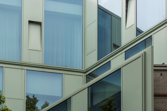 View of modern architecture with reflective glass windows creating a geometric pattern against a pale green facade, Muenster, North Rhine-Westphalia, Germany.
