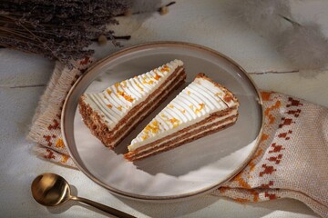 A delightful scene unfolds showcasing two slices of carrot cake adorned with creamy frosting and vibrant orange zest, resting on a plate with a nearby golden spoon