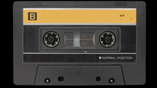 Vintage Audio Cassette Reels Spinning. Retro compact cassette tape with spinning reels on black background.	