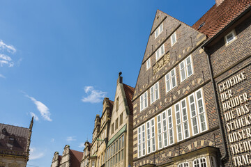 View of aged brick buildings reach for the clear blue sky, their gabled roofs and white-framed windows creating a timeless architectural tapestry, Bremen, Bremen, Germany.