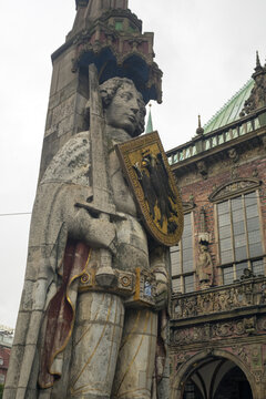 View of a stoic, large stone statue of Roland holding a sword and shield stands tall against the backdrop of the ornate Bremen Rathaus, Bremen, Bremen, Germany.