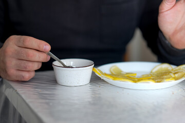 Morning sunlight illuminates a person savoring lemon slices with honey at breakfast