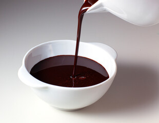 A stream of hot chocolate falls into a bowl.