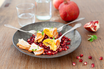 Plate with pomegranate seeds, cured meats, and an orange.
