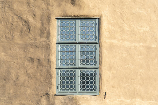 View of blue, multi-pane window nestled in a textured, earthy-toned wall, bathed in warm sunlight at Kalmar Castle, Kalmar, Kalmar County, Sweden.