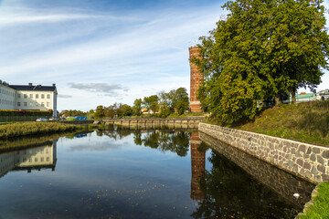 View of the tranquil canal reflecting the towering brick structure and lush trees under a vast sky, a blend of nature and architecture, Kalmar, Kalmar County, Sweden.