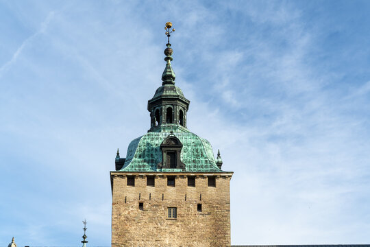 View of the tower with a copper-green roof rises against a clear blue sky, its golden finial glinting in the sunlight, Kalmar, Kalmar County, Sweden.