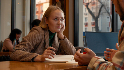 Happy young woman smiling while working or studying with a partner