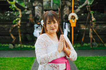 Balinese Woman in Traditional Kebaya with Namaste Gesture in Front of Pura