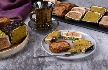 Assortment of sliced ​​Turkish delight with cream filling, pistachio, almond, hazelnut on a gray table. Mixed Turkish delight for tea. Local name: fistikli fitil lokum