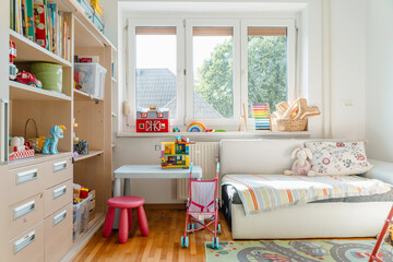 Tidy children room. Interior decor of clean children's room. Organizing storage in kids room: bookshelves and educational and soft toys. Montessori education. A childs bedroom with toys and books. © nataliaderiabina