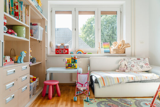 Tidy children room. Interior decor of clean children's room. Organizing storage in kids room: bookshelves and educational and soft toys. Montessori education. A childs bedroom with toys and books.