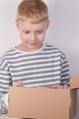 Real child opening a cardboard package with interest, perfect for concepts of delivery, unboxing and surprises.
